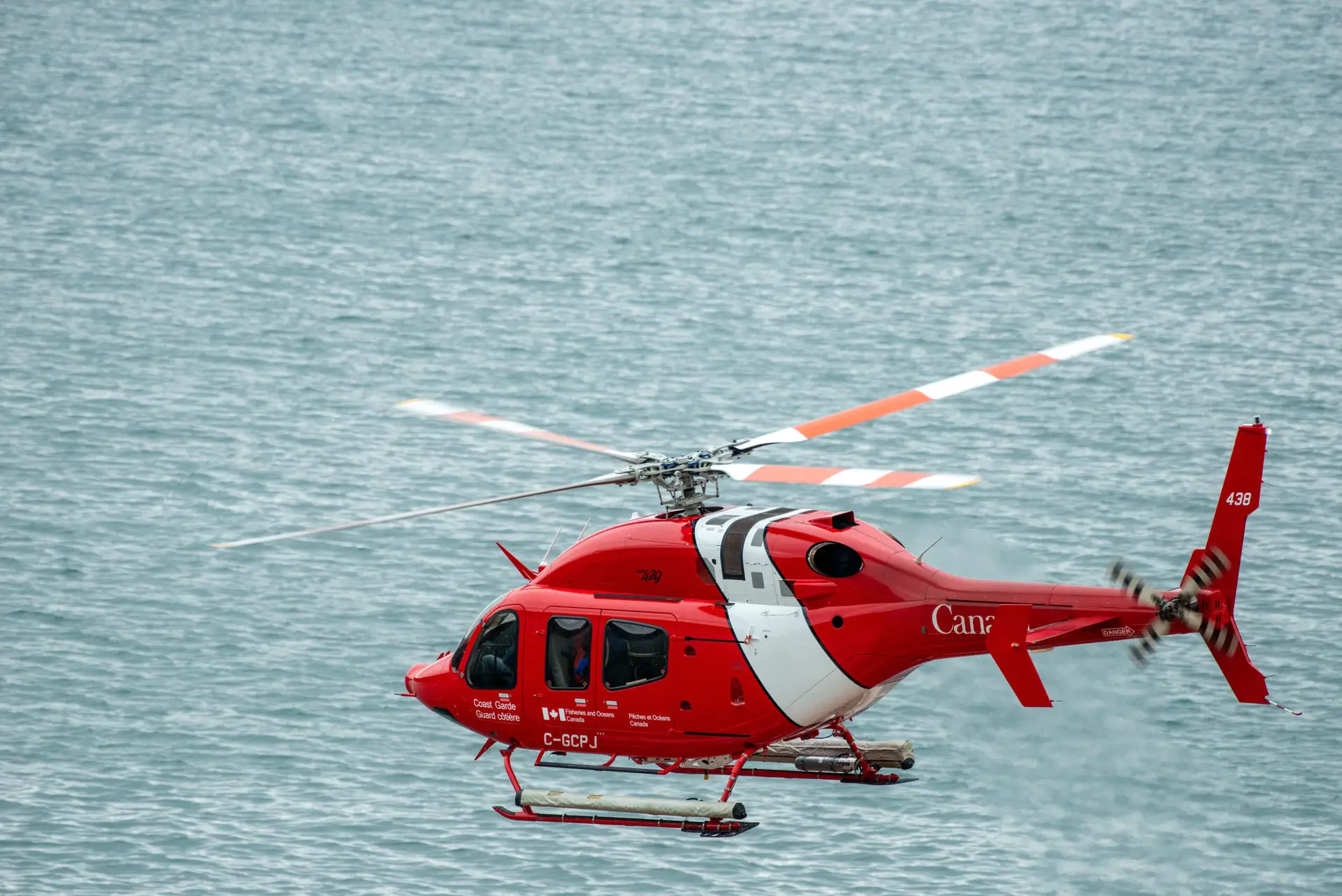 St. John's, Newfoundland, Canada-August 5, 2023: A Canadian Coast Guard emergency search and rescue cormorant helicopter or chopper flies low to the ground over the blue Atlantic Ocean.