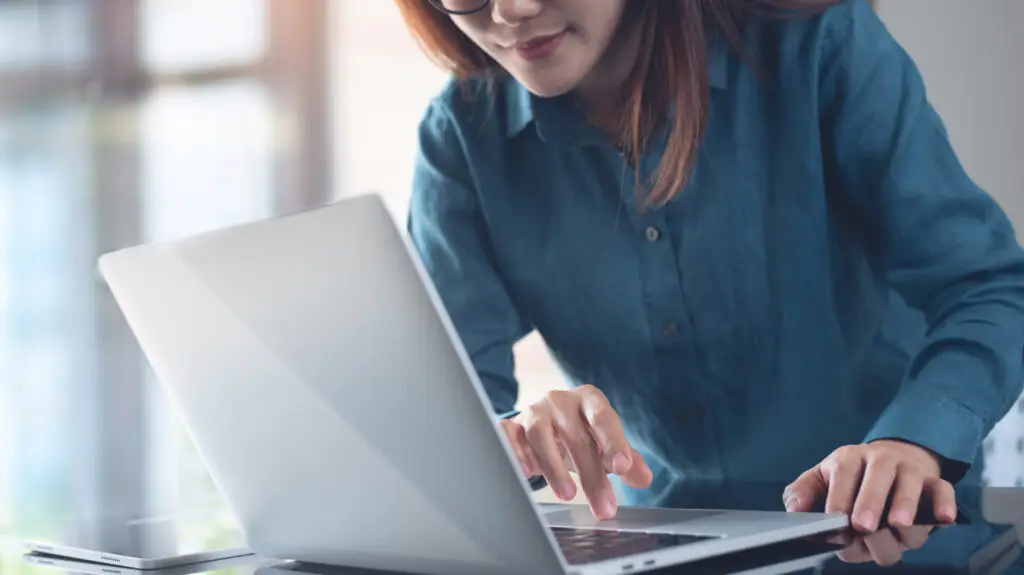 Business woman working on laptop computer with digital tablet on office table, close up. Female freelancer busy working on laptop, surfing the internet, searching the information, freelance lifestyle