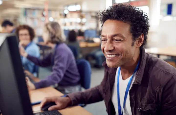 Image of a man smiling at his desktop computer