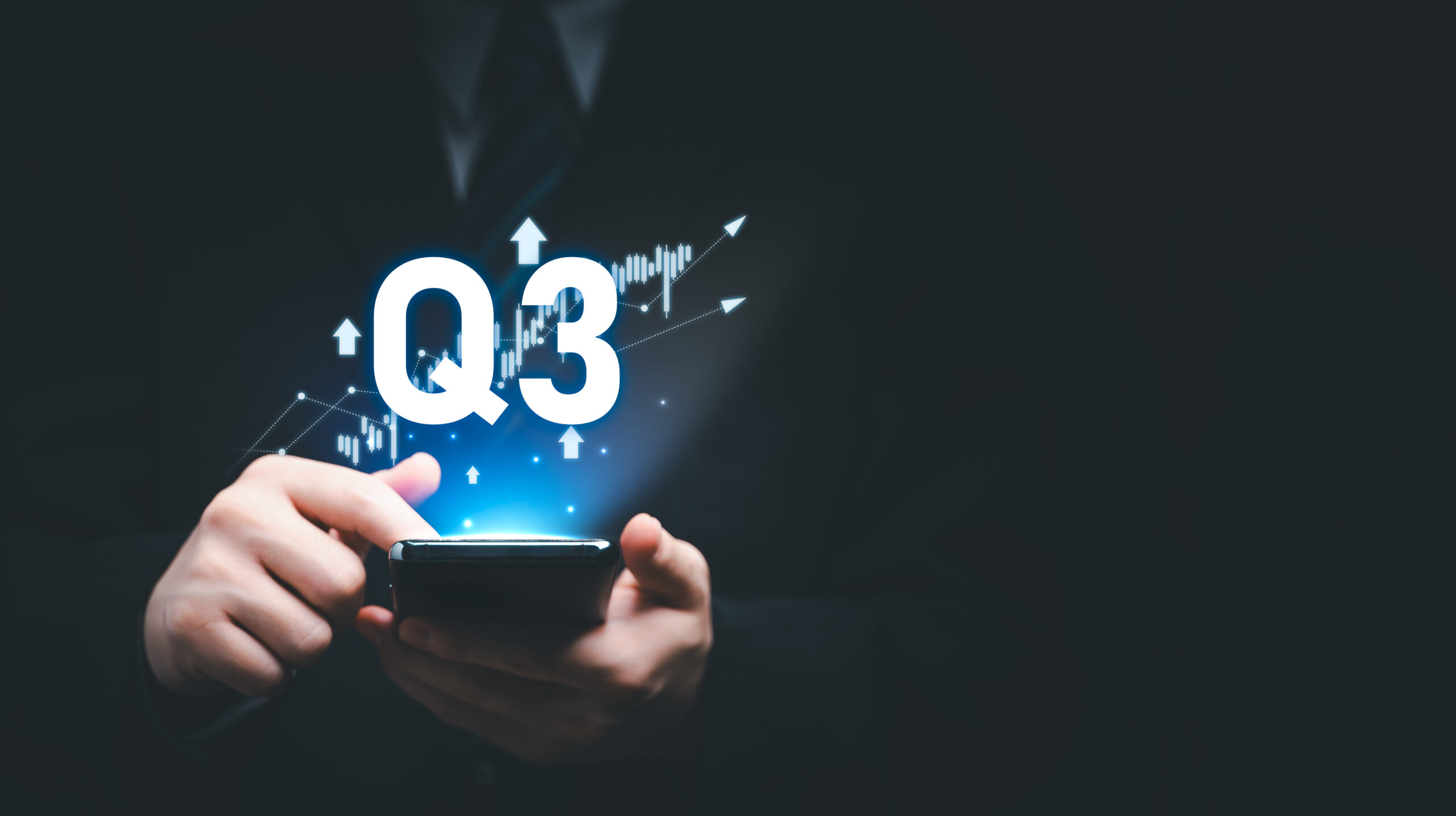 Man holding smartphone with glowing Q3 and upward trending graph