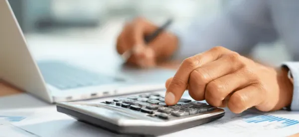 A person uses a calculator, with financial documents spread out on the desk